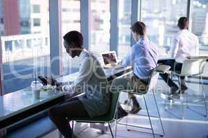 Executive using mobile phone and laptop while having snacks