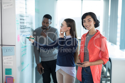 Female executive using mobile phone with colleagues in background