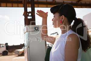 Woman shielding her eyes at petrol pump station