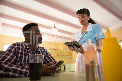 Man giving order to waitress on digital tablet