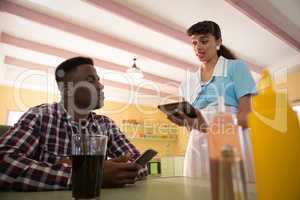 Man giving order to waitress on digital tablet