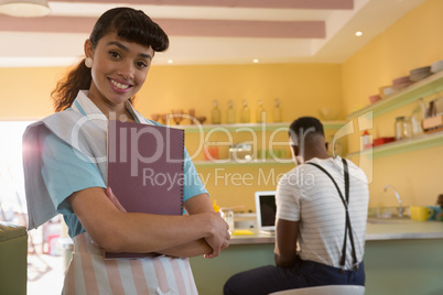 Waitress holding menu while man using laptop