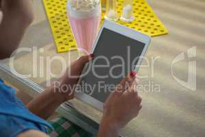 Woman using tablet while having milkshake in the restaurant