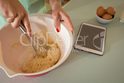 Young woman whisking mixture into bowl in the kitchen