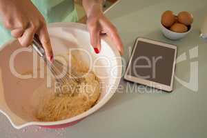 Young woman whisking mixture into bowl in the kitchen