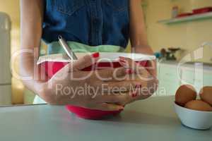 Hands of woman holding bowl in the kitchen at home