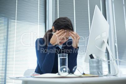 Tensed female executive sitting at desk