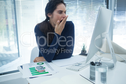 Tired female executive yawning at desk