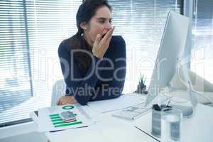 Tired female executive yawning at desk