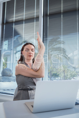 Female executive performing yoga at desk