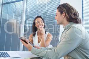 Business executives discussing over digital tablet at desk