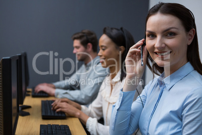 Business executives with headsets using computers at desk