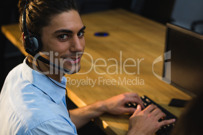 Male executive with headset using computer at desk