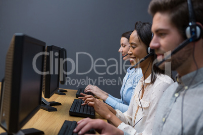 Business executives with headsets using computers at desk