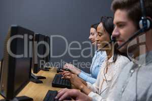 Business executives with headsets using computers at desk