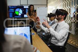 Businessmen using virtual reality headset in conference room