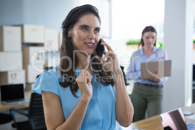 Smiling female executive talking on phone