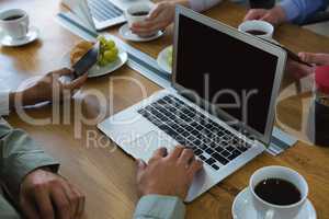 Male executive having coffee while using laptop