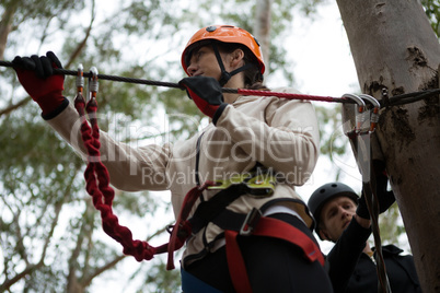 Young woman wearing safety helmet getting ready to cross zip line