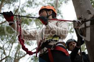 Young woman wearing safety helmet getting ready to cross zip line