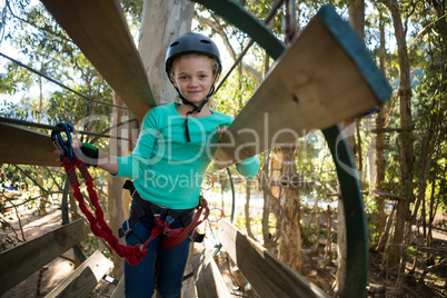 Little girl wearing helmet standing in wooden trolley