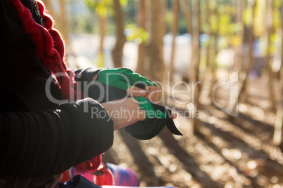 Little girl removing her hand gloves in the forest