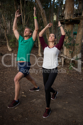 Woman performing stretching exercise with the help of trainer