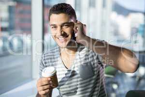 Portrait male executive talking on mobile phone while having coffee