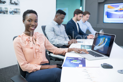 Male and female executives using laptop during meeting