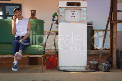 Woman talking on mobile phone at petrol pump station