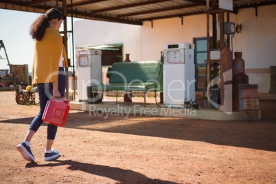 Woman walking with a petrol can at petrol pump