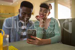 Smiling couple sitting on couch using a mobile phone