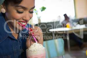 Happy young woman having milkshake in the restaurant