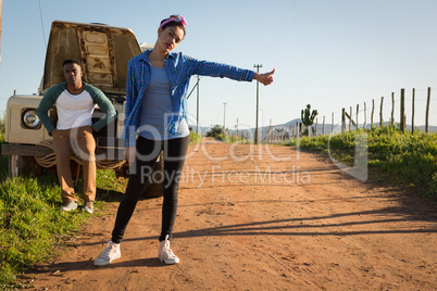 Woman hitchhiking on dirt track