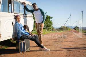 Couple sitting on suitcase at countryside