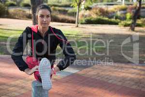 Fit woman stretching her leg on bollard