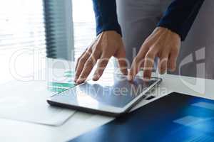 Mid section of female executive using digital tablet at desk