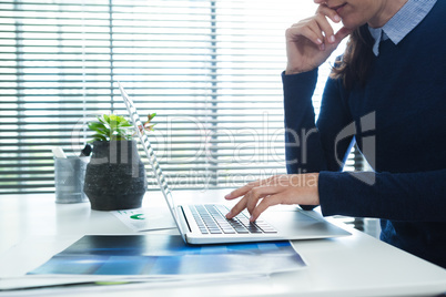 Female executive using laptop at desk