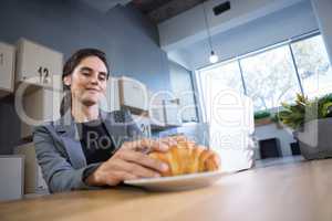 Female executive having croissant at table