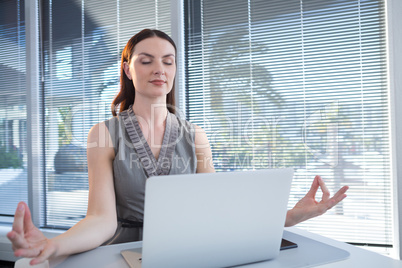 Female executive performing yoga at desk