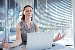 Female executive performing yoga at desk