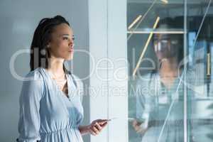 Female executives standing with mobile phone near window