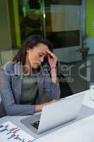 Tensed businesswoman using laptop at desk