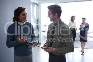 Male executives discussing over digital tablet