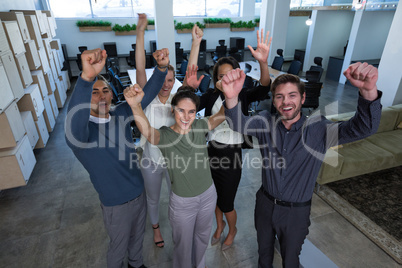 Business colleagues standing with arms up in office