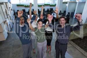 Business colleagues standing with arms up in office