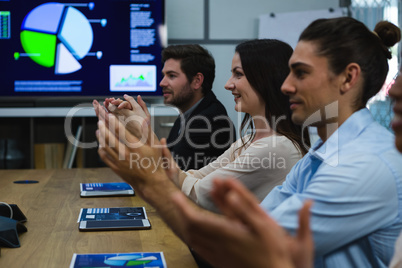 Business colleagues clapping hands in meeting