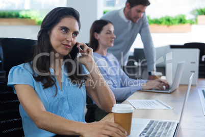 Female executive talking on phone while holding coffee mug