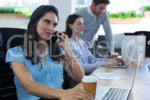 Female executive talking on phone while holding coffee mug