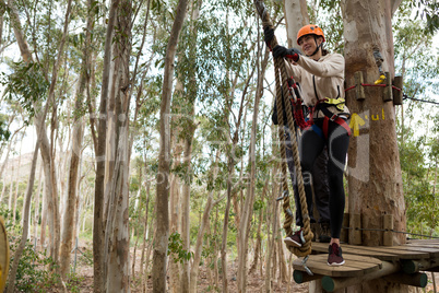 Woman wearing safety helmet getting ready to climb on zip line
